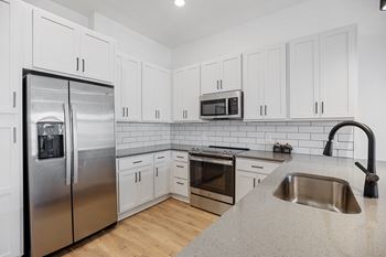a kitchen with white cabinets and stainless steel appliancesat Oak Grove at Blake Farm, Wilmington, North Carolina